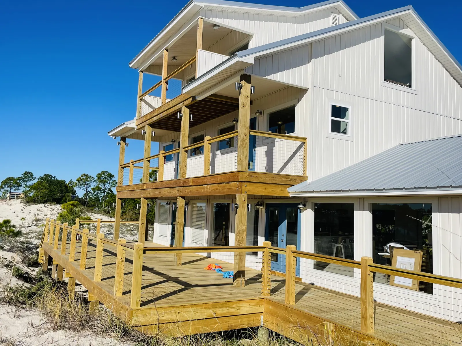 Multi-level beach house decks with wood posts and cable railing on the dunes