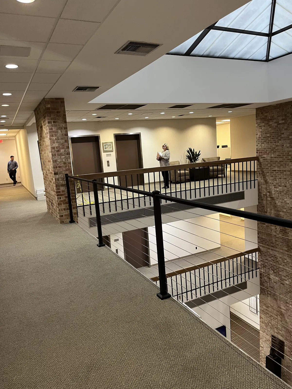 Stainless cable railing on black posts along an open second-floor walkway in a commercial building