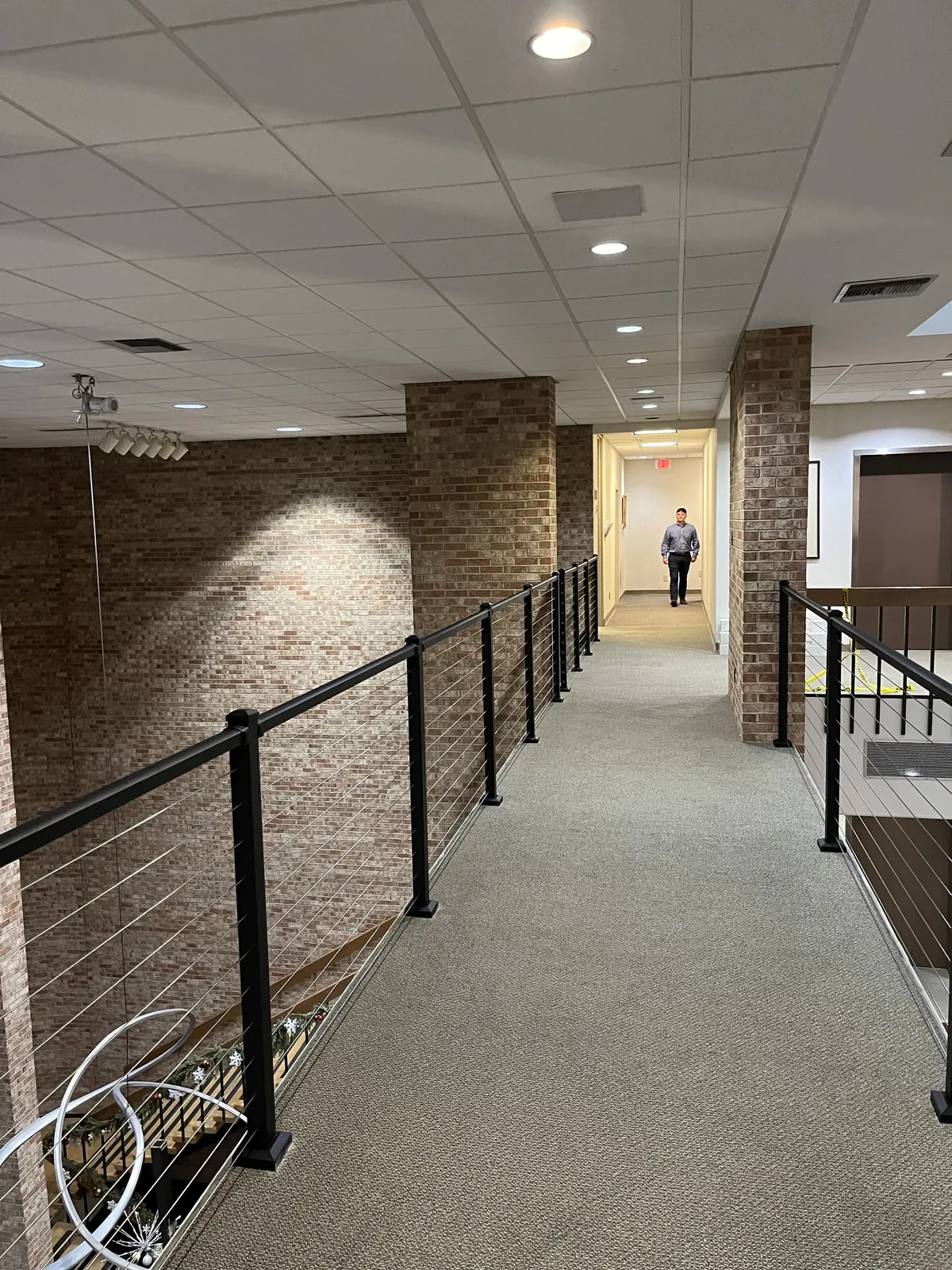 Interior corridor guard with stainless cable railing on black posts