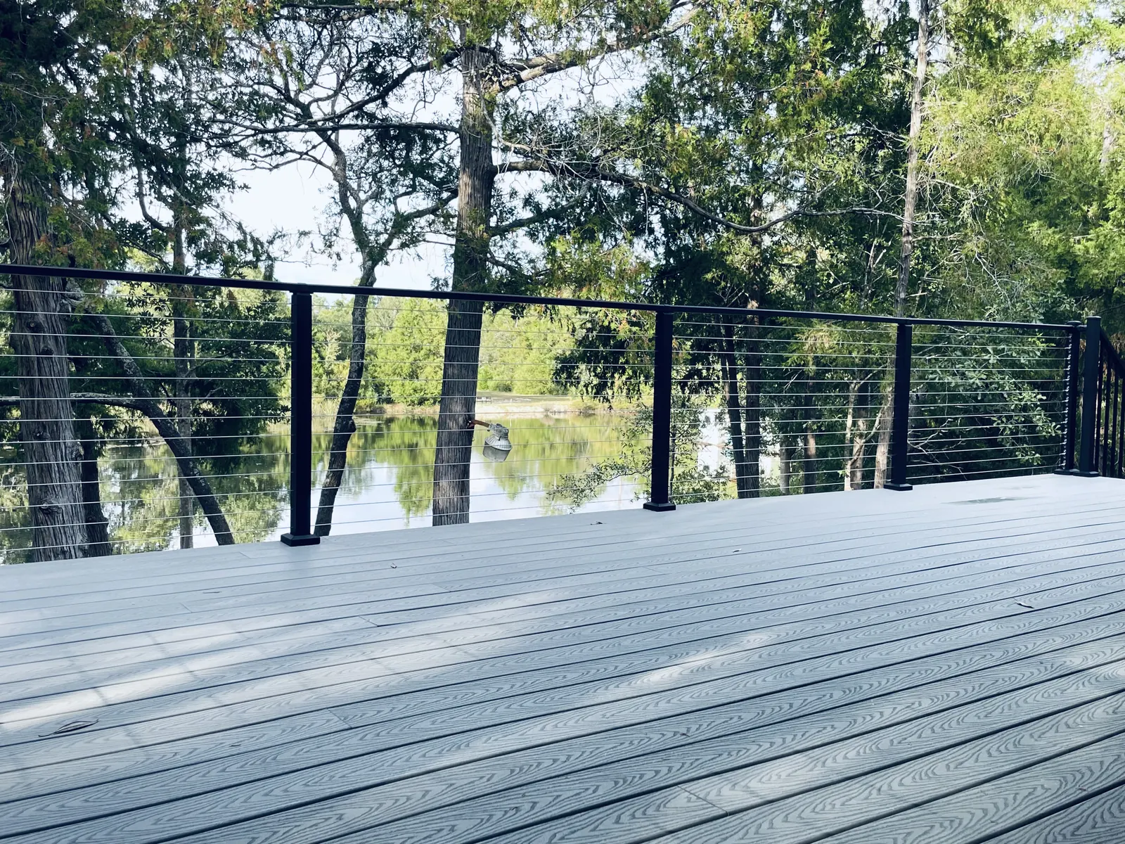 Composite deck with stainless cable railing on black posts