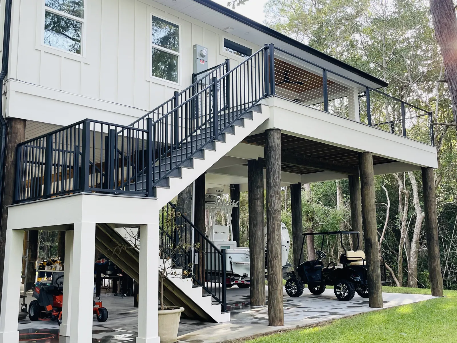 Raised home with stainless cable railing on black posts along the deck and exterior staircase