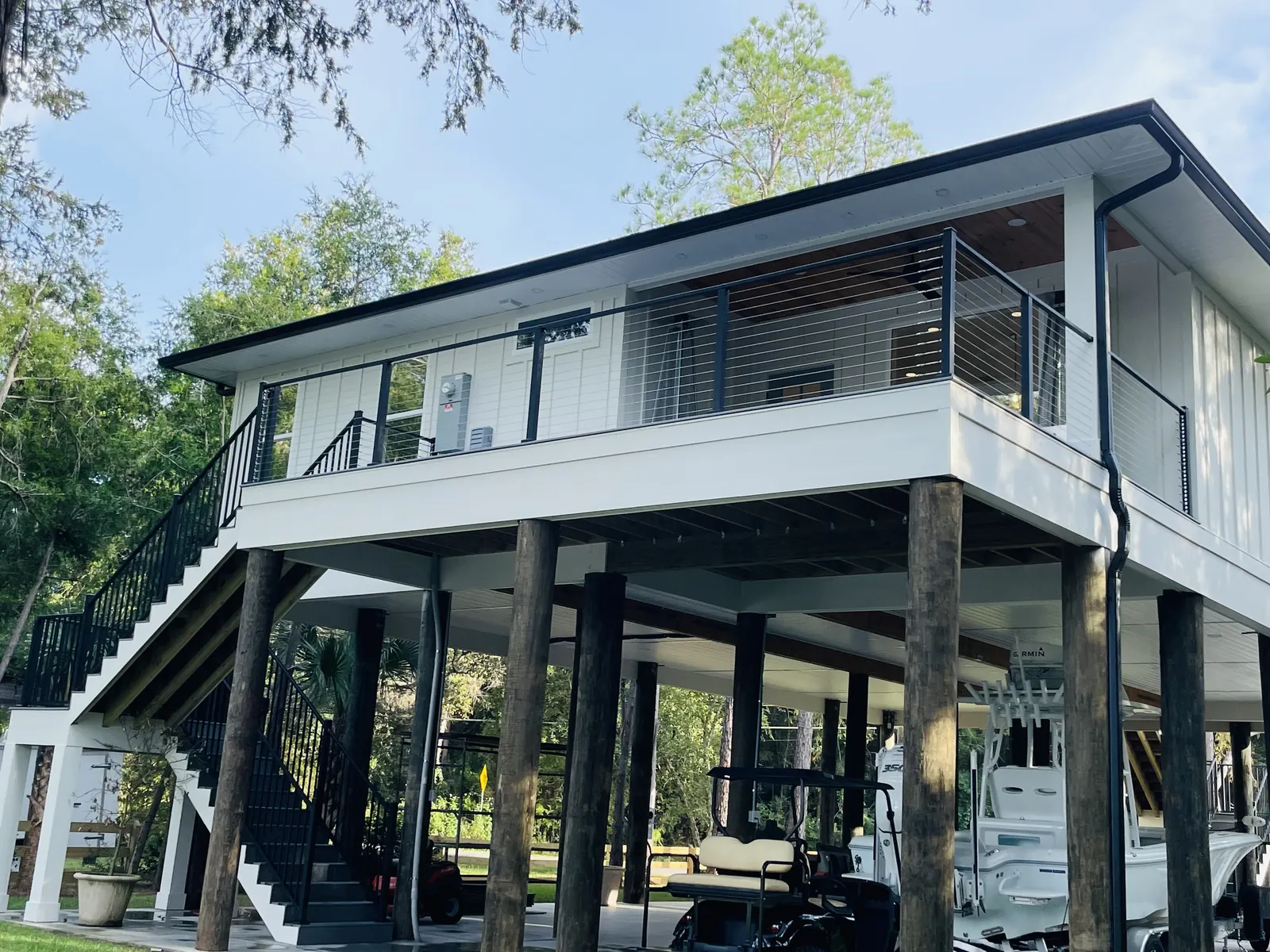 Stilt home with a wraparound deck and stainless cable railing on black posts