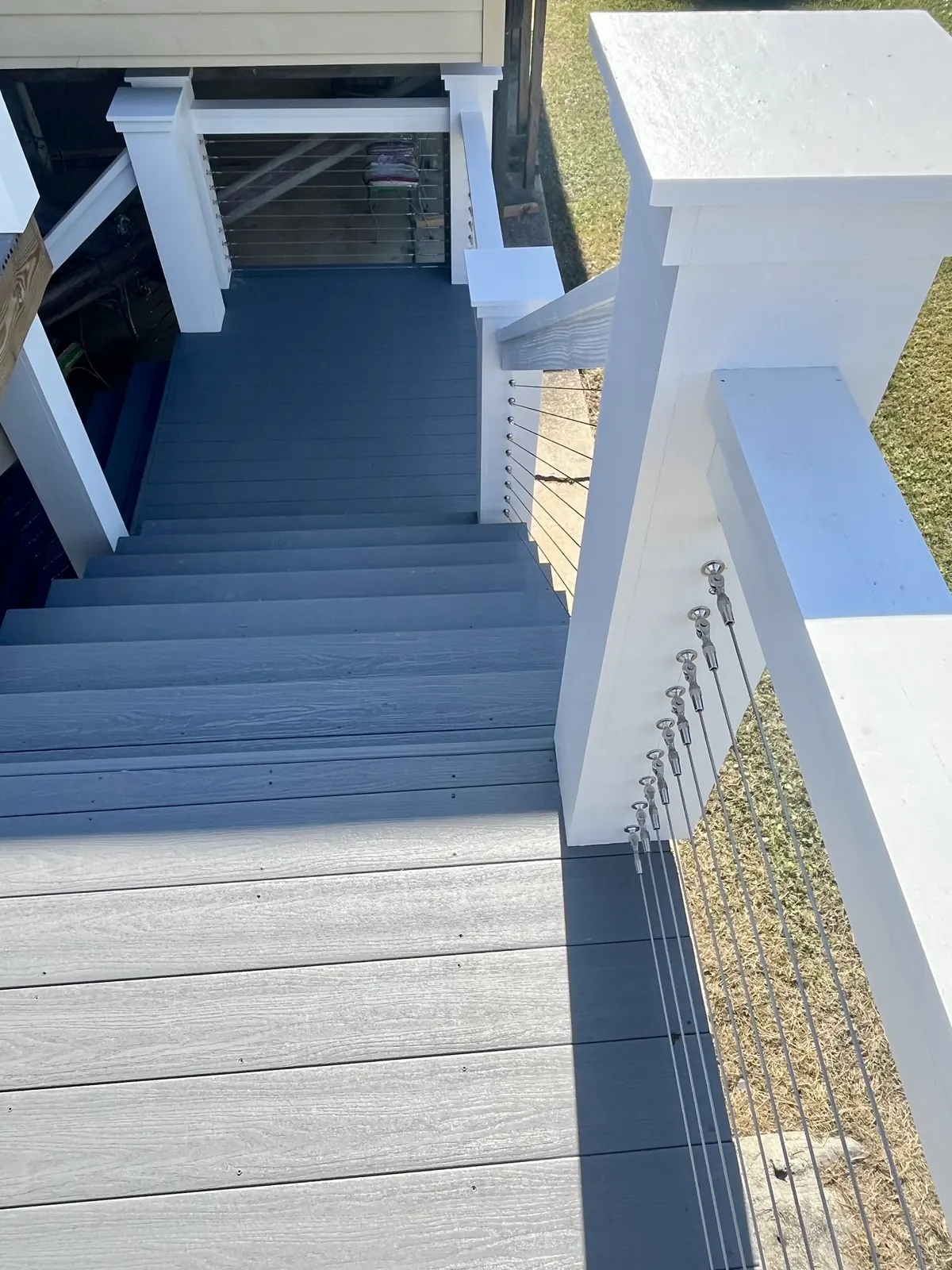 Deck stairs with white posts and stainless cable railing