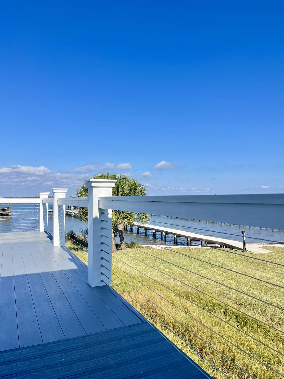 White posts with 316 stainless cable railing on a waterfront deck