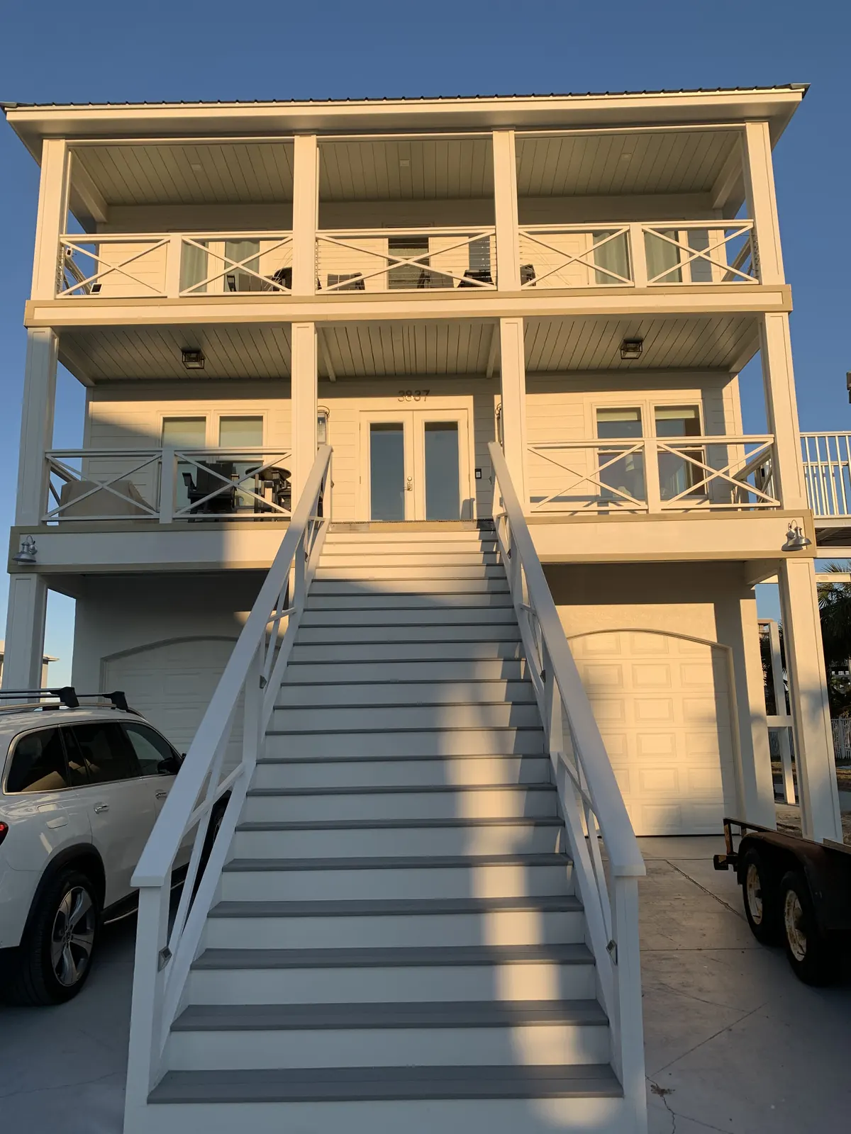Coastal home with X-pattern railing frames and cable infill on two porch levels