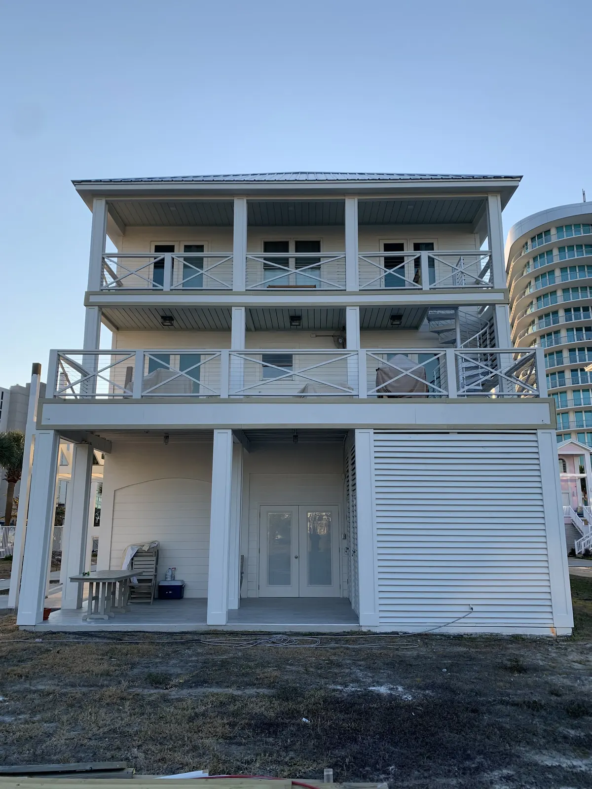 Three-story beach home with X-pattern cable railing on each porch