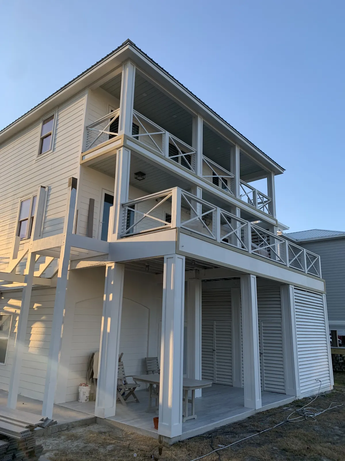 Side view of stacked porches with X-pattern railing and cable infill