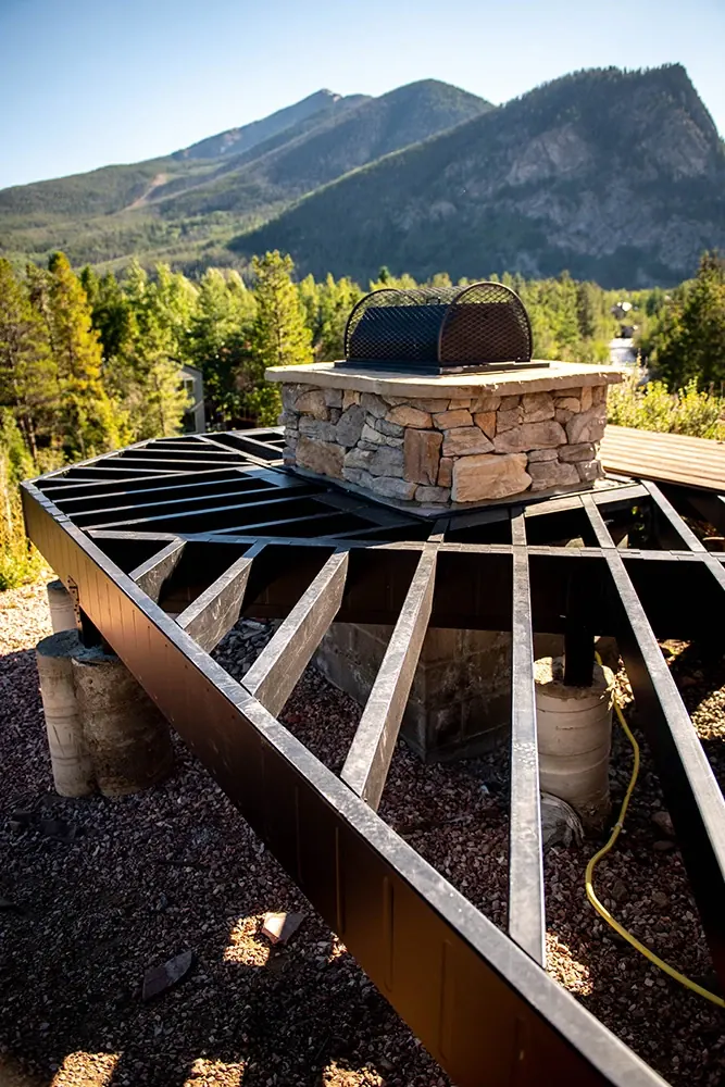 Fortress Evolution steel deck framing beside a stone outdoor kitchen