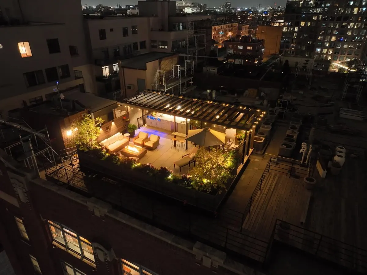 Rooftop deck at night with a Fortress steel pergola and city skyline