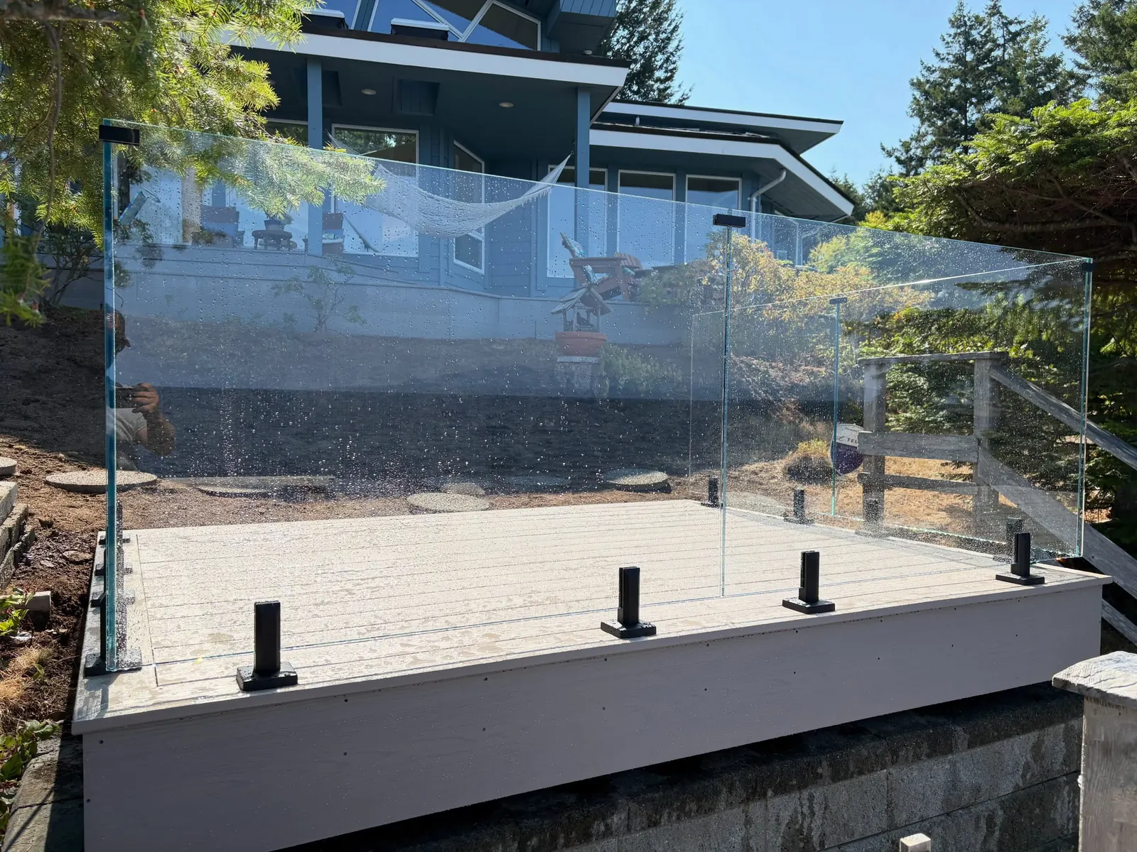 Frameless glass railing on black spigots around a new deck