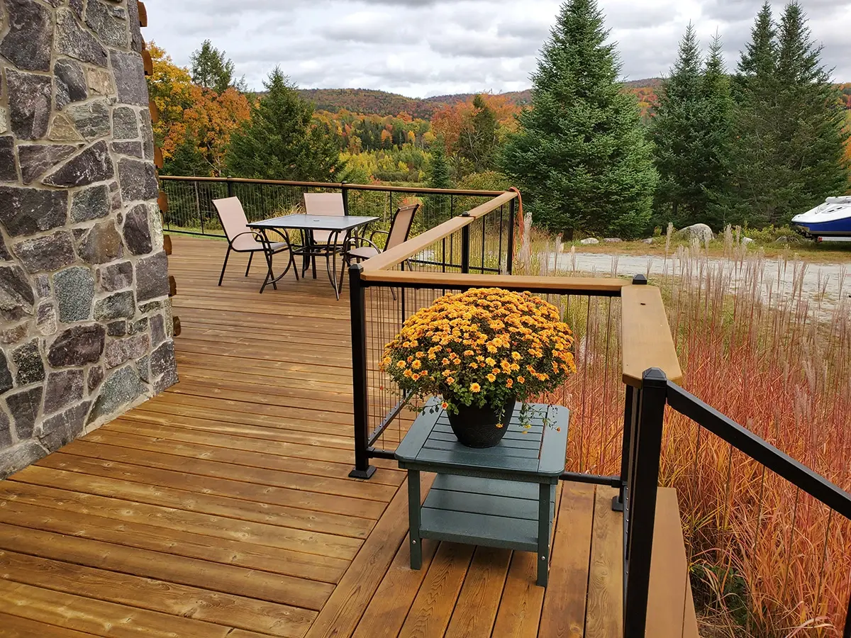 Wood deck with black railing and stone chimney in fall