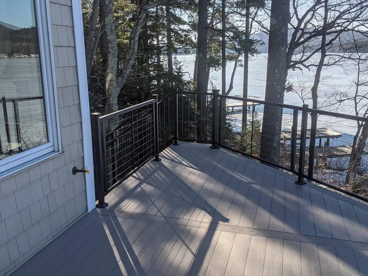 Black cable railing with black posts beside a lake house