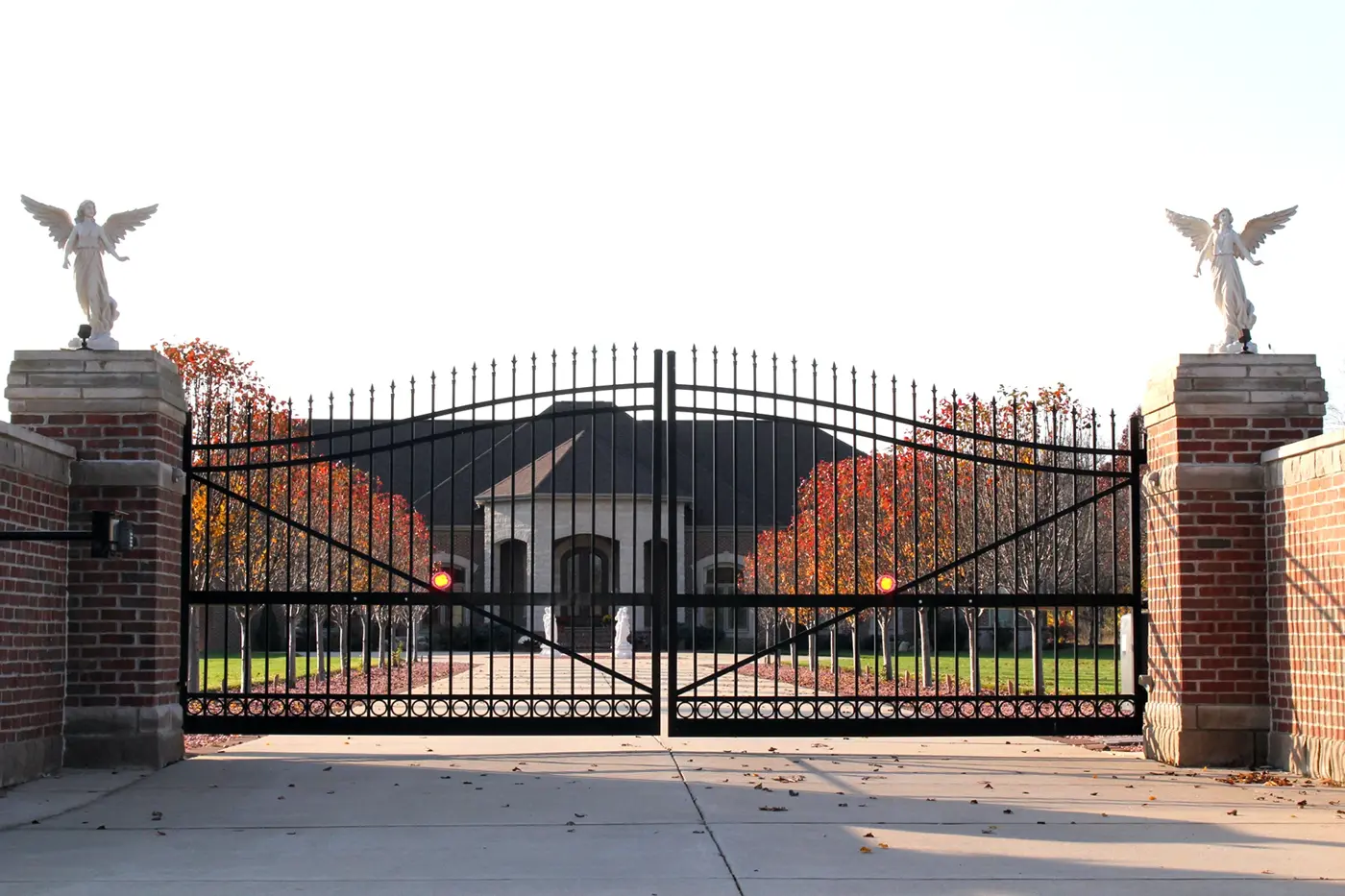 Black ornamental double driveway gate between brick piers