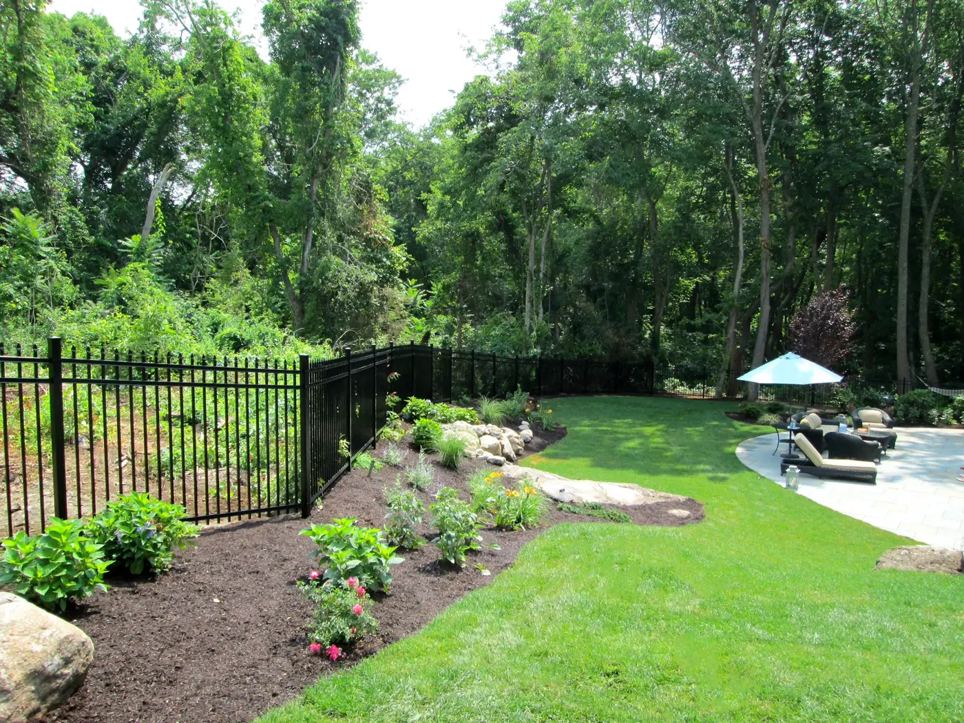 Black aluminum fence along a landscaped garden and lawn