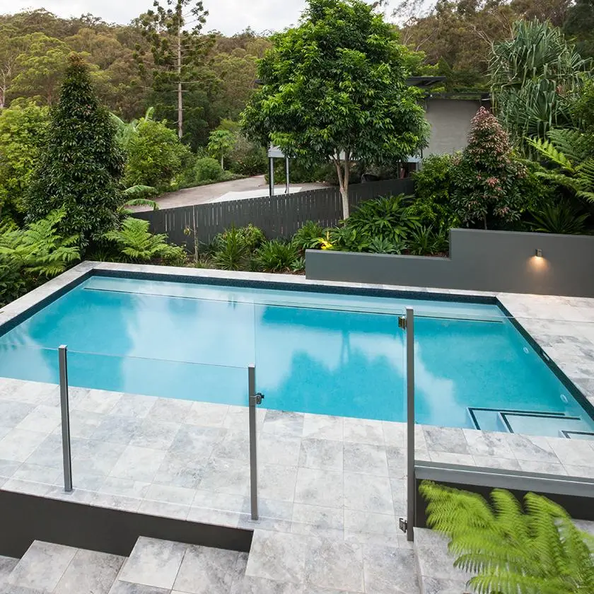 Glass pool fence panels with a gate on a residential pool deck