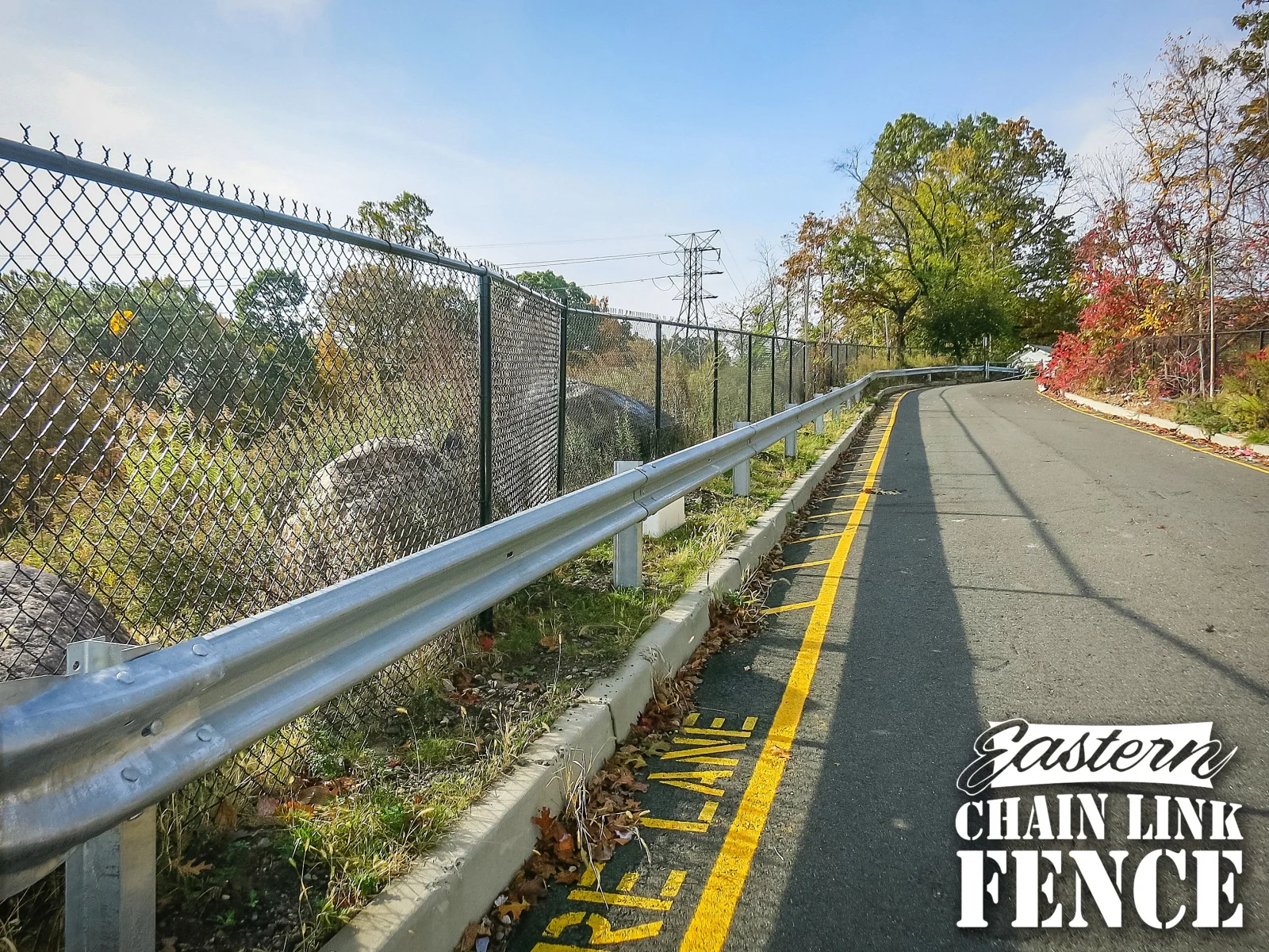 Steel guide rail beside a chain-link fence