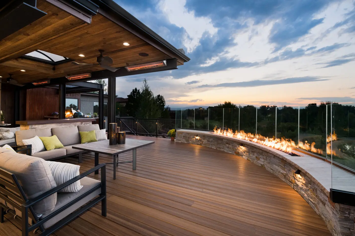 Covered deck with lounge seating and fire table at sunset