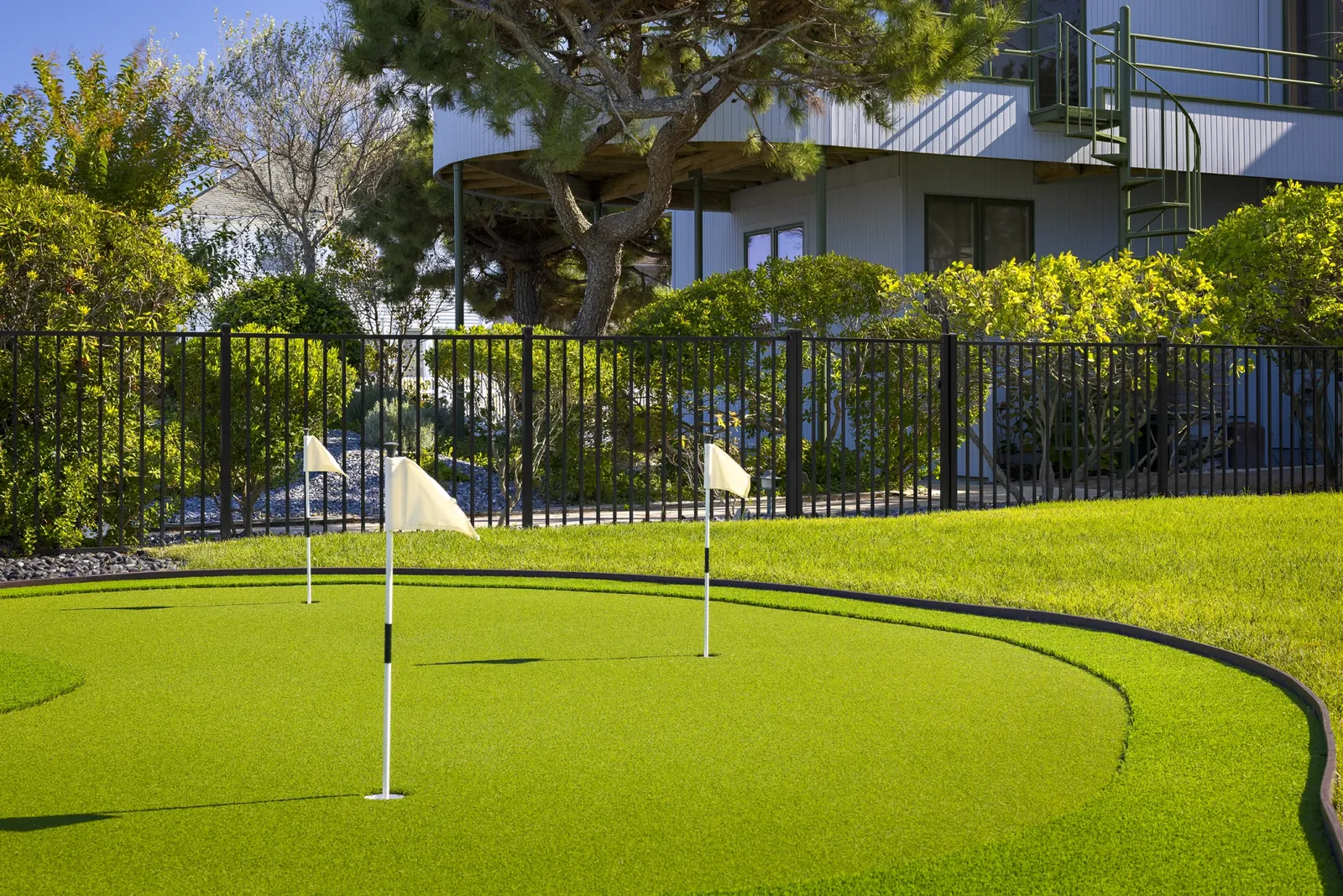 Black aluminum fence around a backyard putting green