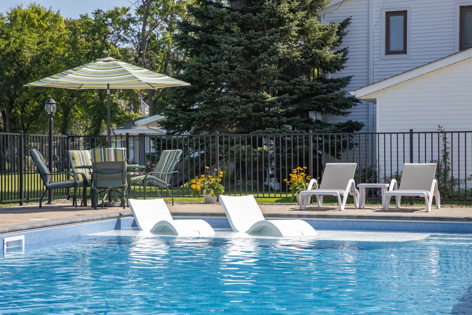 Black aluminum pool fence with lounge chairs