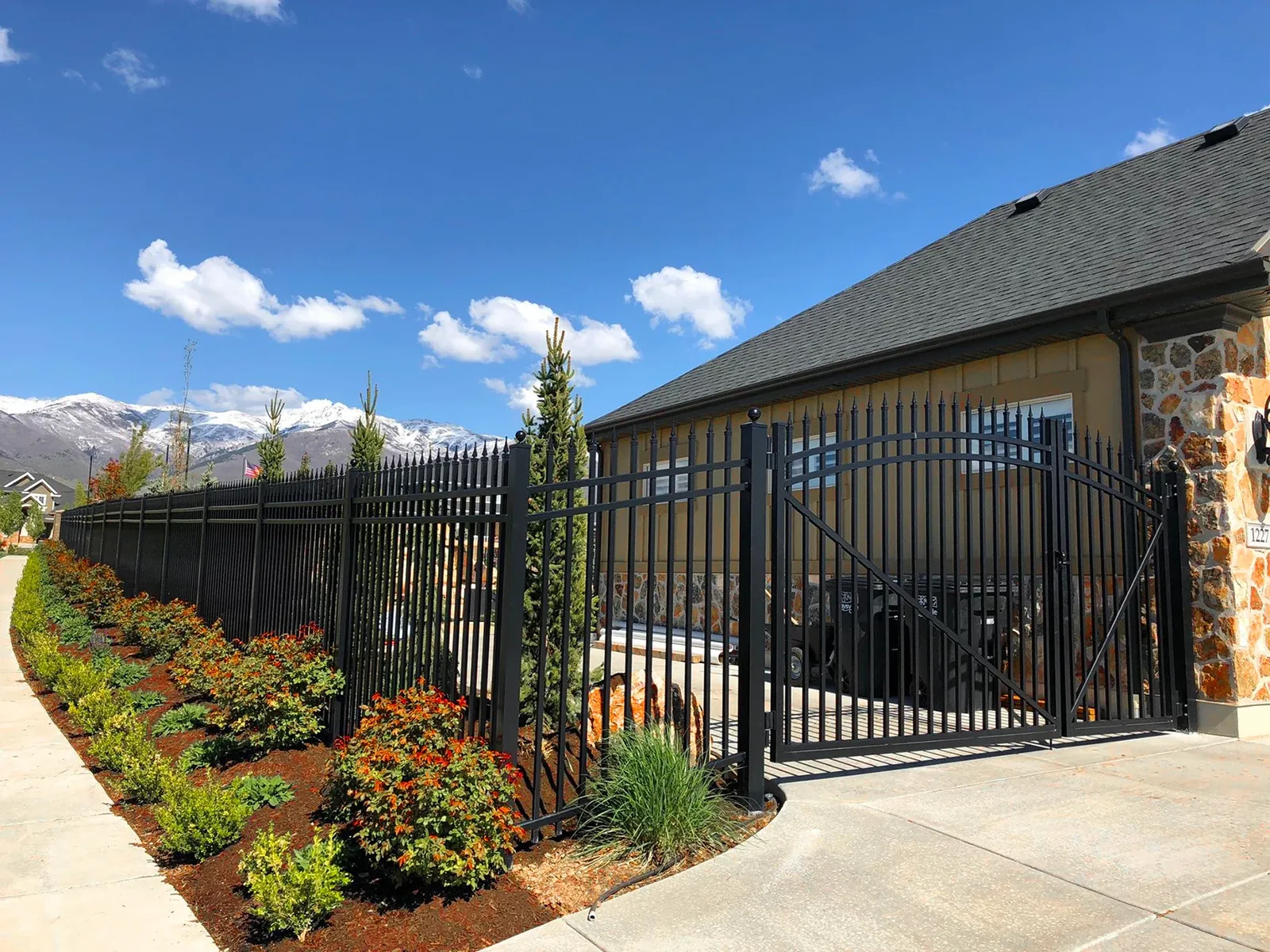Black aluminum fence and gate beside a home