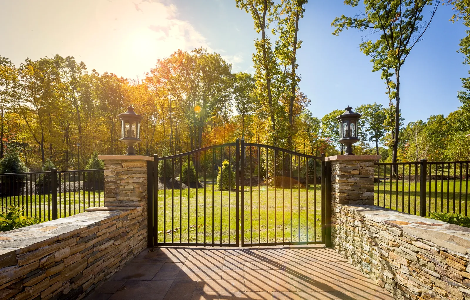 Black aluminum gate between stone pillars