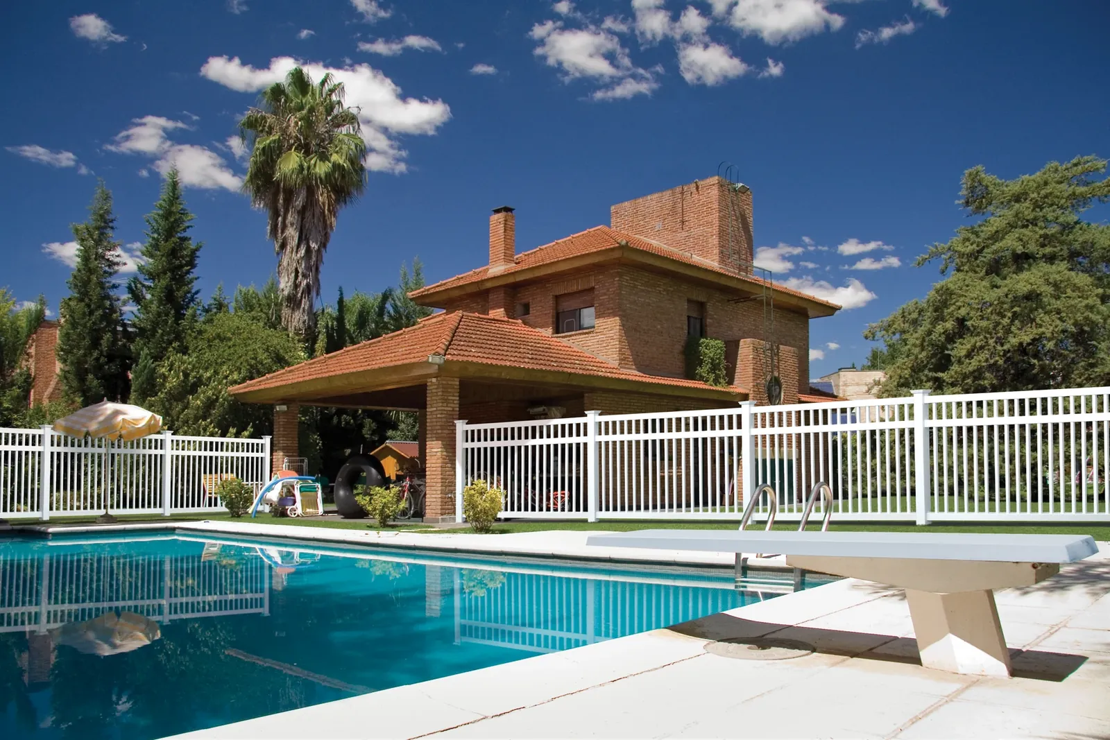 White vinyl pool fence at a Mediterranean-style home