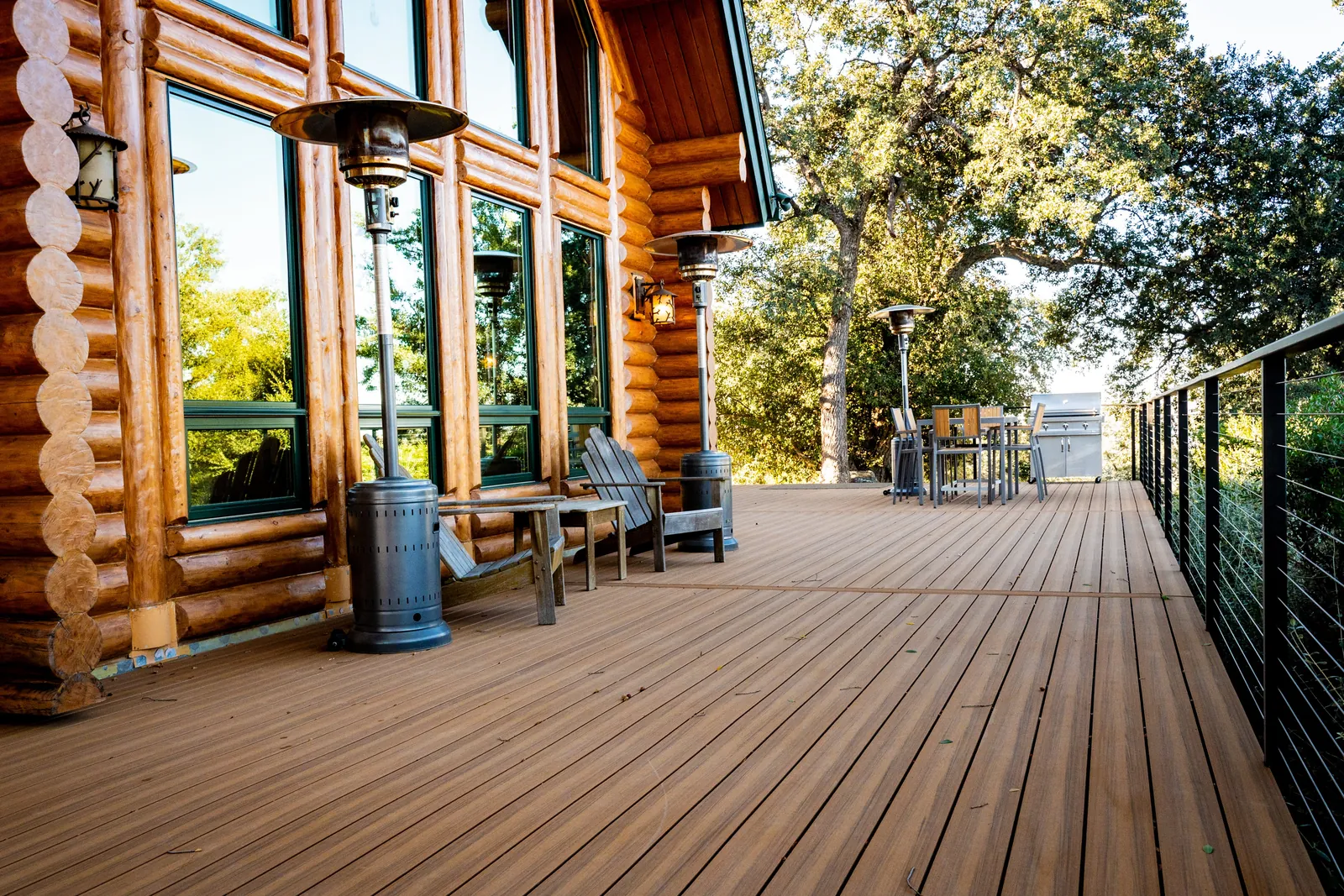 Cable railing deck along a log home