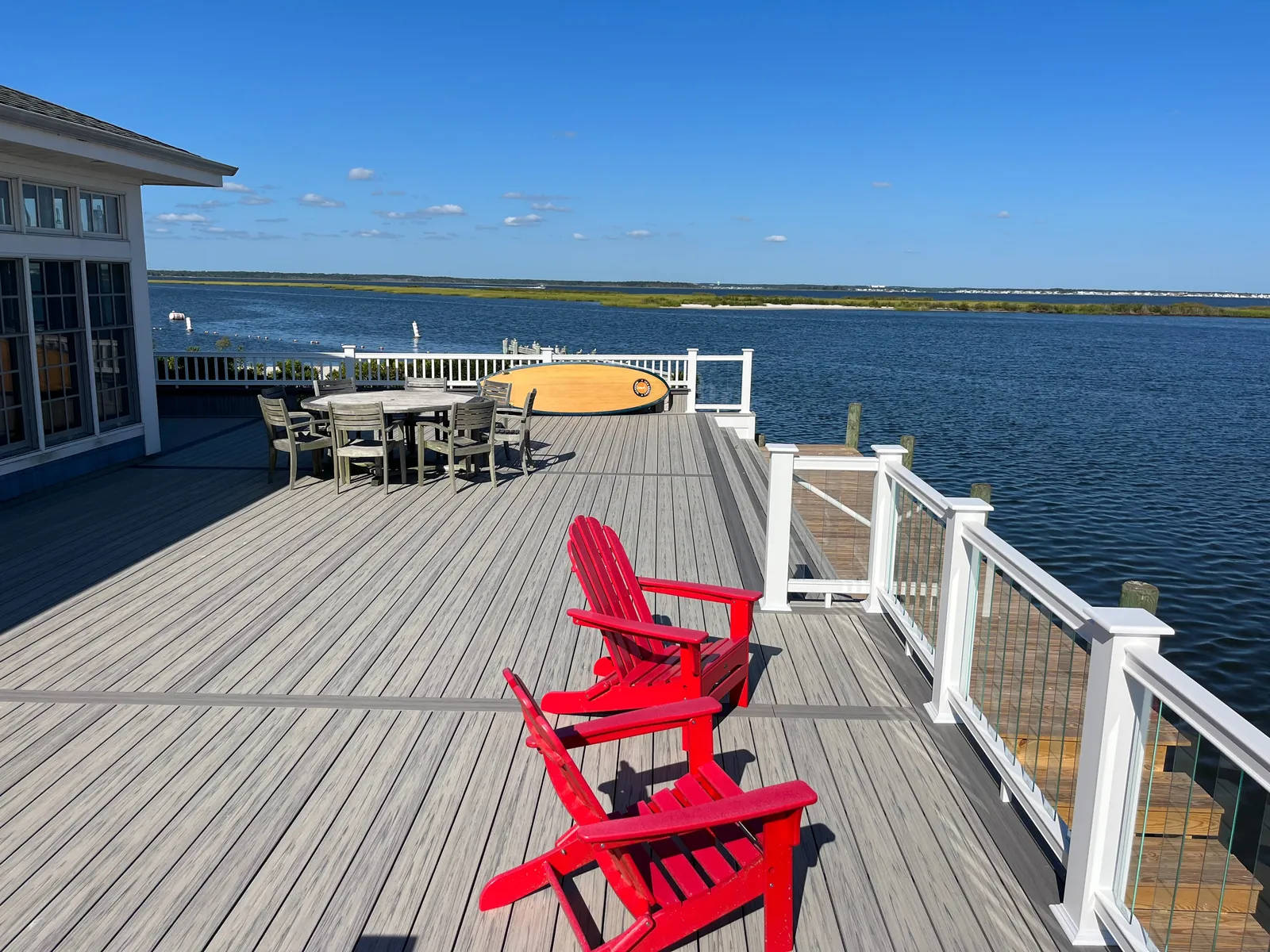 Long waterfront dock deck with red Adirondack chairs