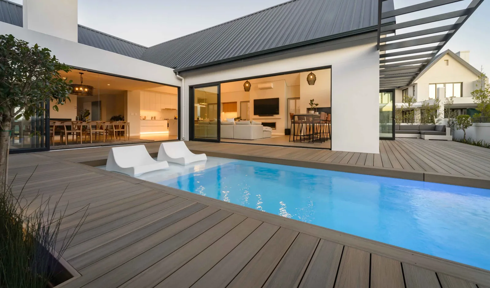 Pool deck off a modern home with in-pool loungers