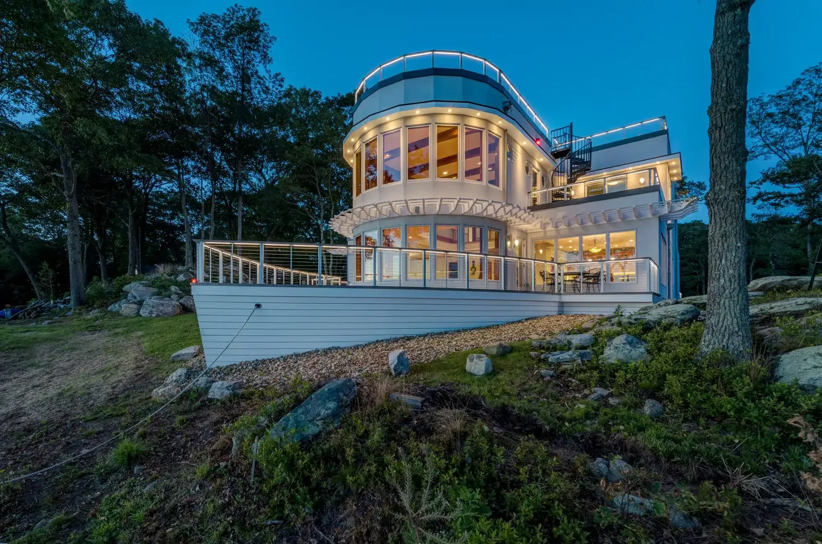Waterfront home with cable railing balconies at dusk