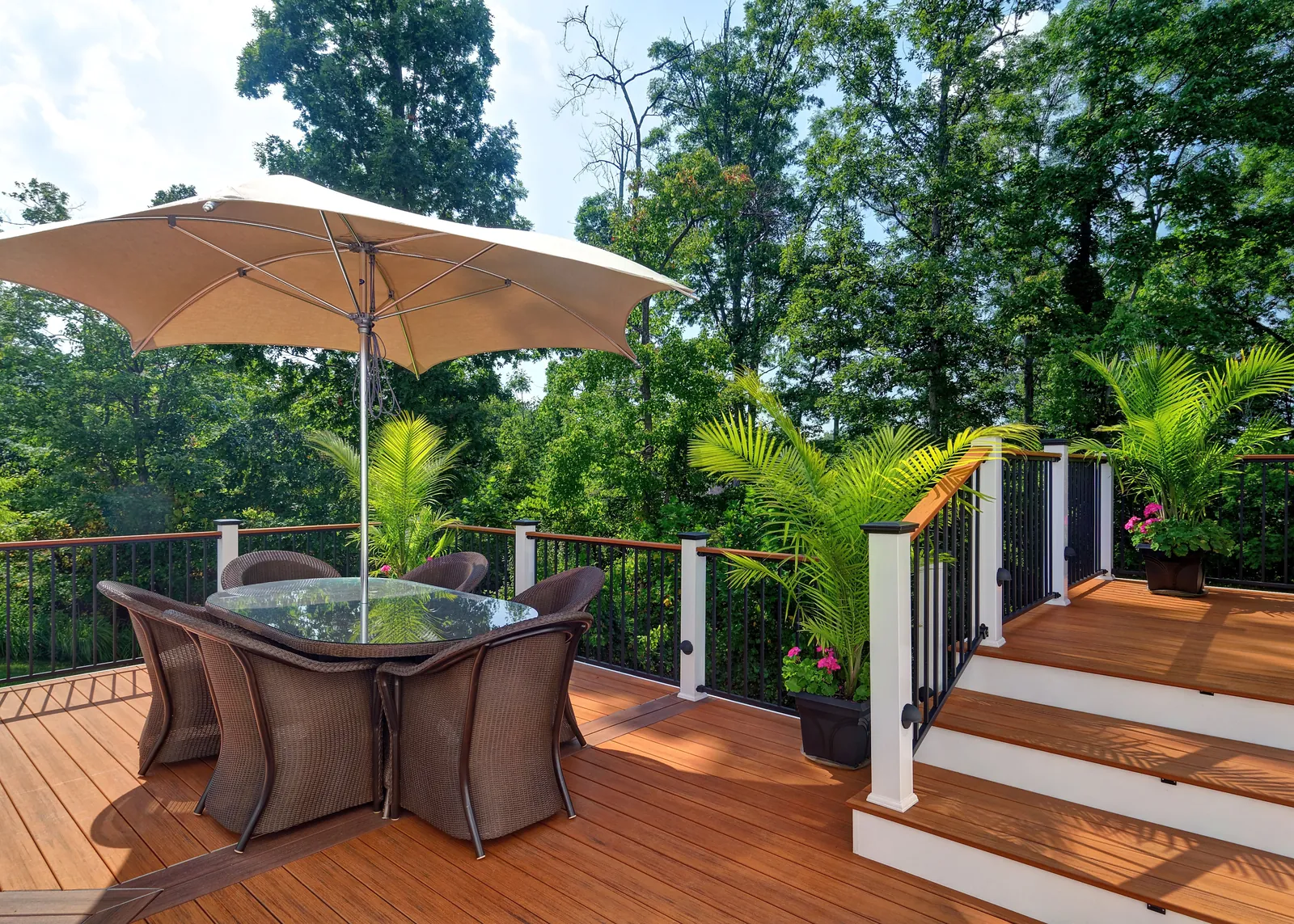 Deck with white railing, umbrella table and tropical plants