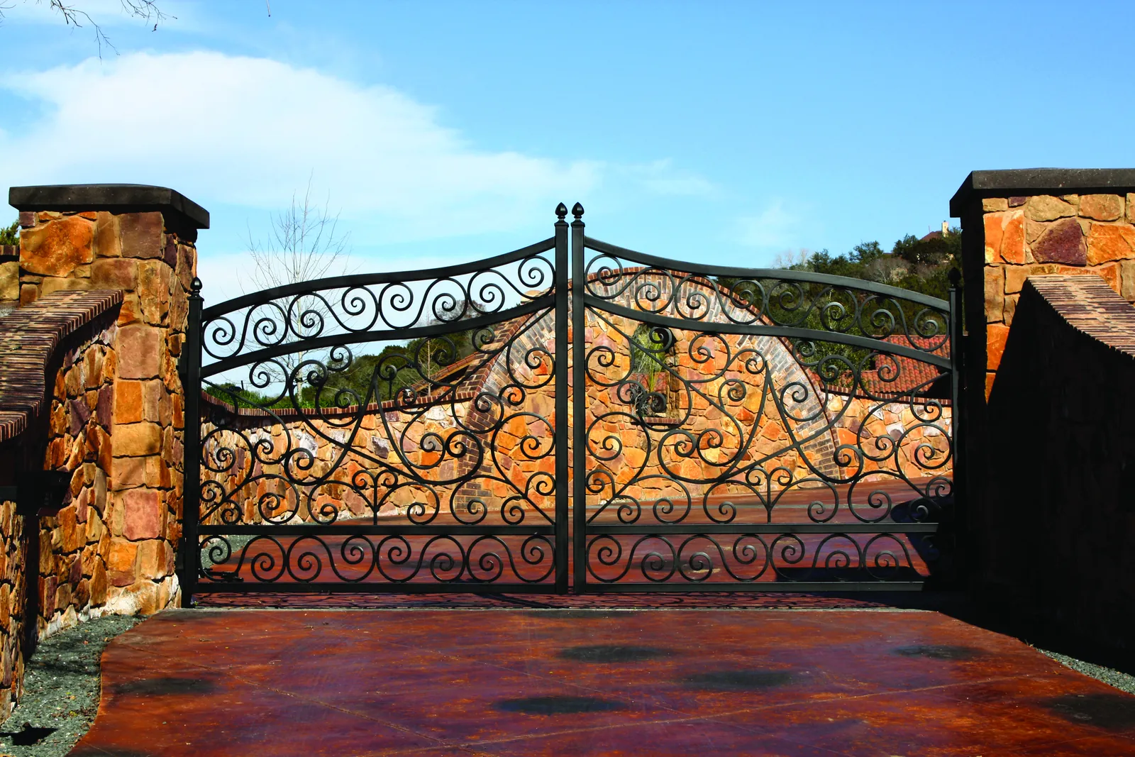 Ornamental steel driveway gate between stone pillars