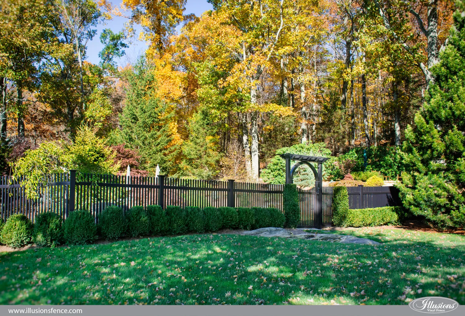 Black aluminum fence through fall landscaping