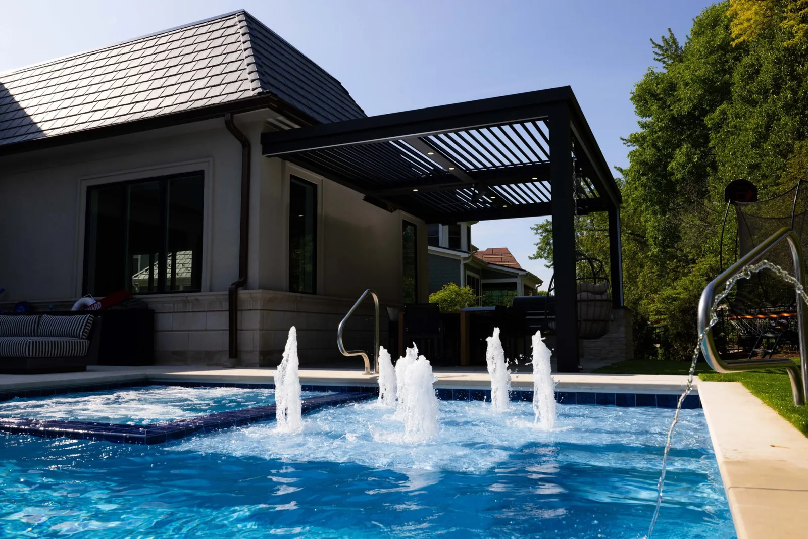 Louvered pergola beside a pool with fountains
