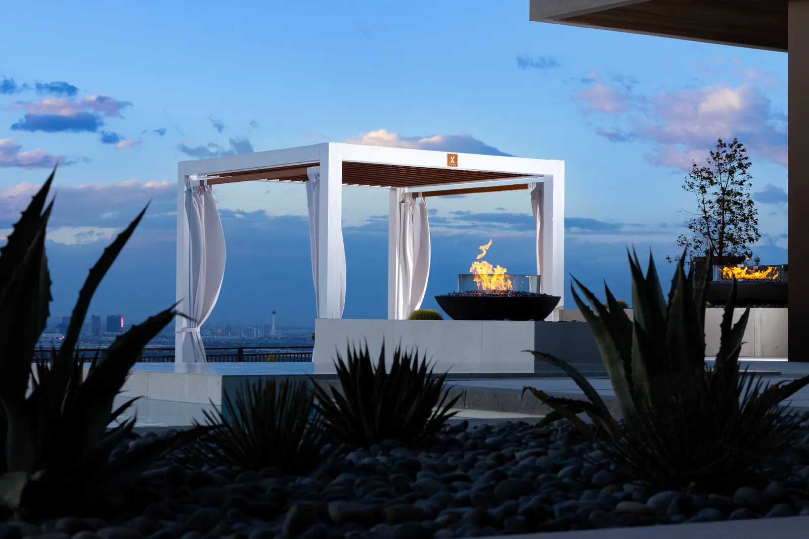 White pavilion with a fire bowl at dusk