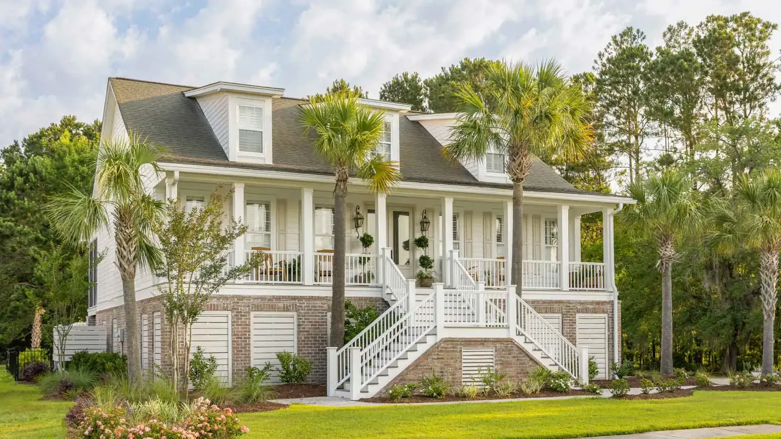 Raised coastal home with white porch decking and stairs