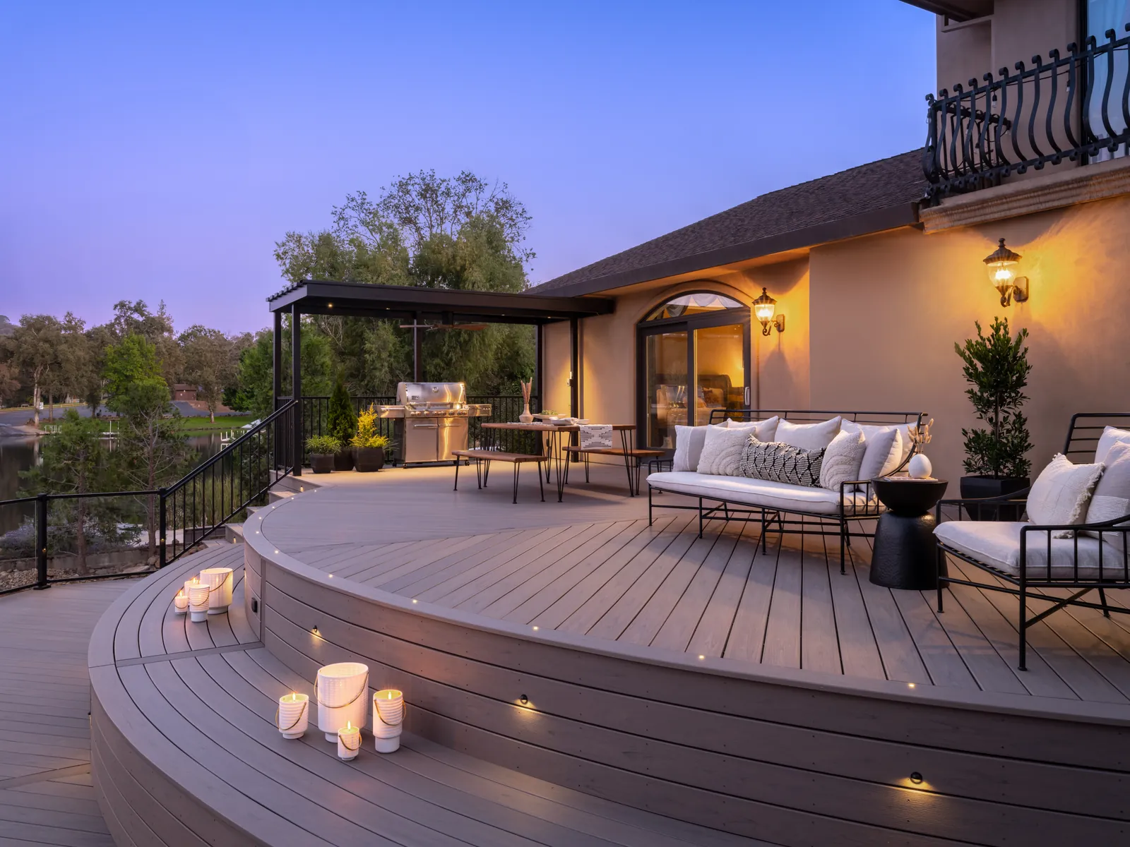 Curved composite deck with lounge seating and step lights at dusk