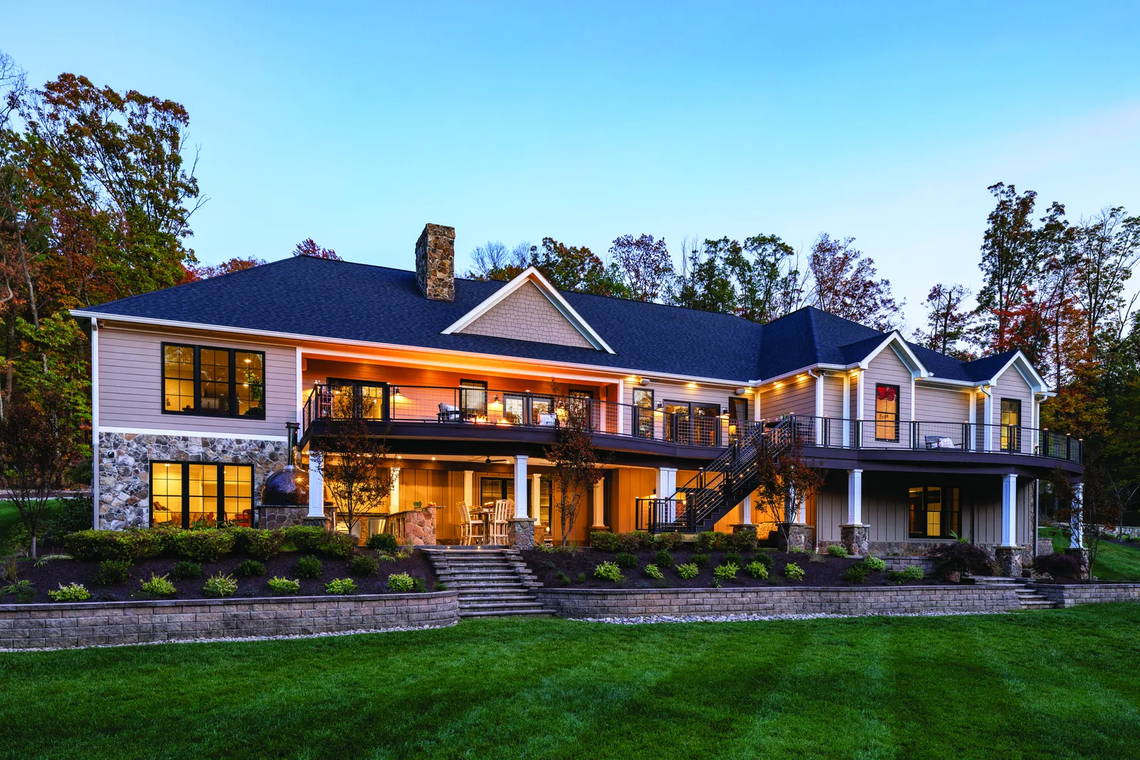 Two-story deck across the back of a lakeside home at dusk