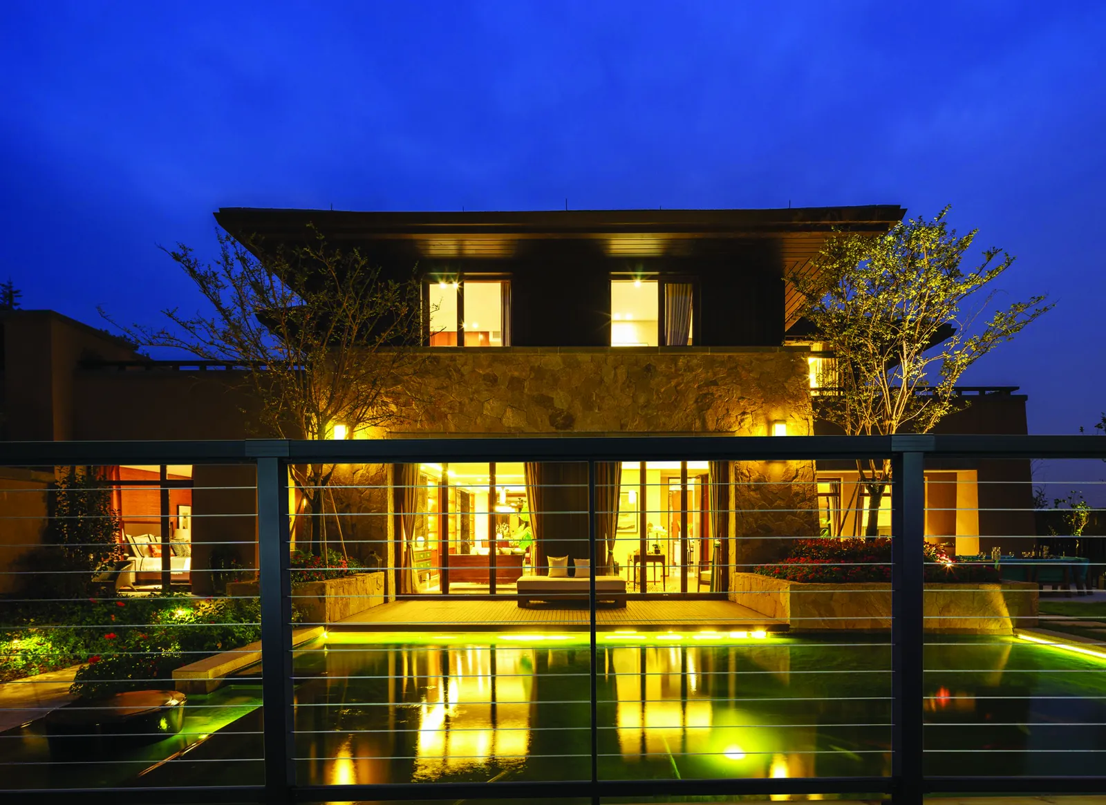 Contemporary home with a lit cable railing terrace at night