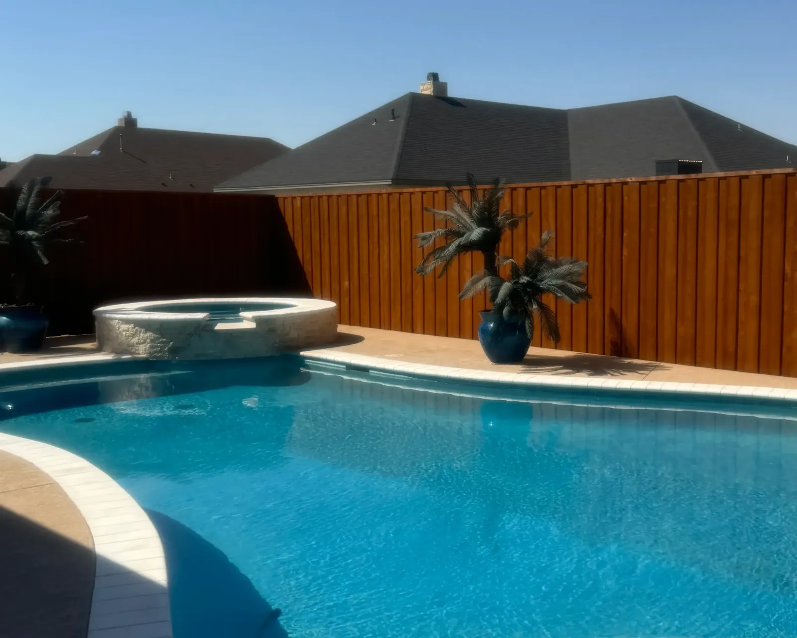 Stained cedar fence behind a backyard pool