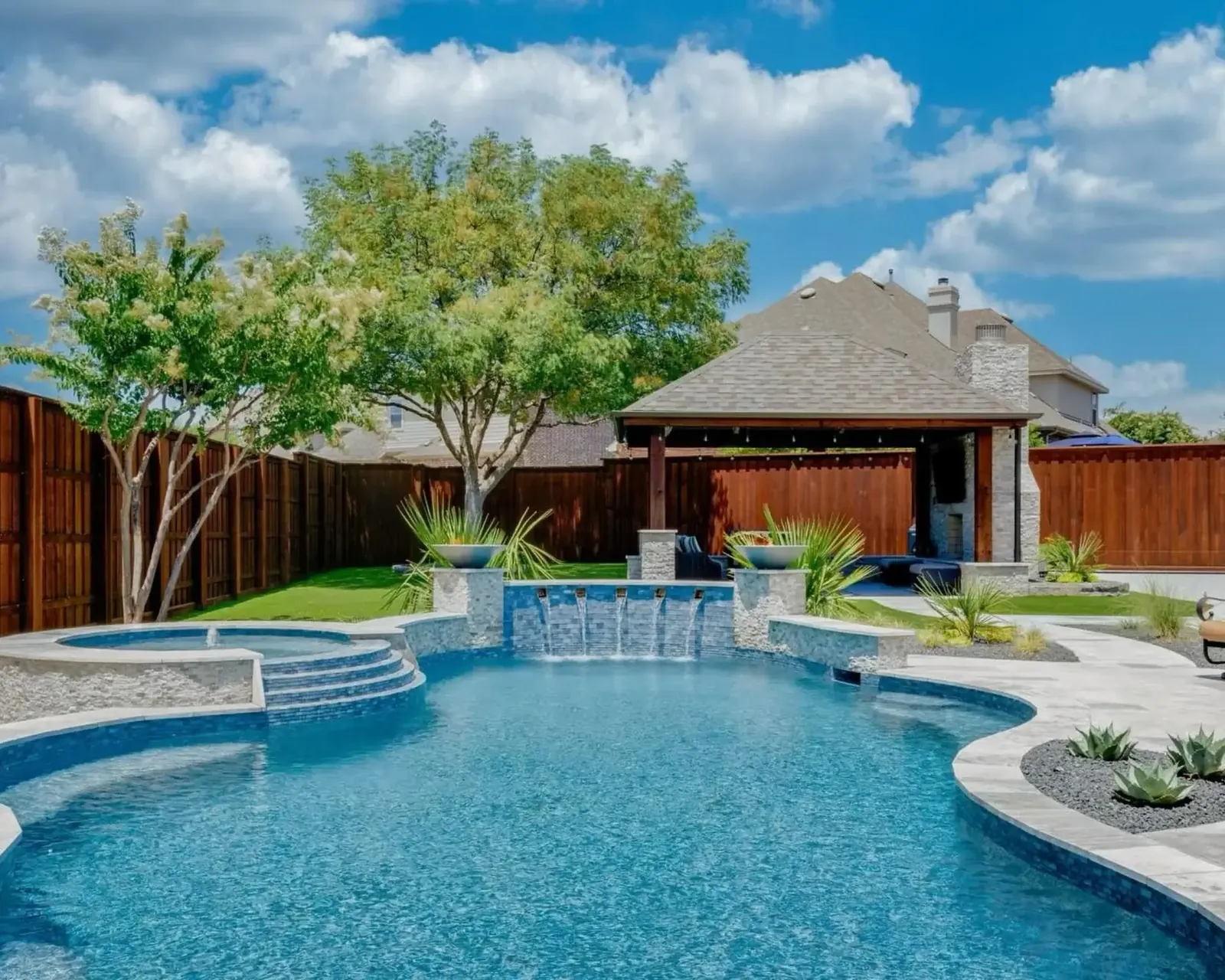 Stained wood fence around a backyard pool and cabana