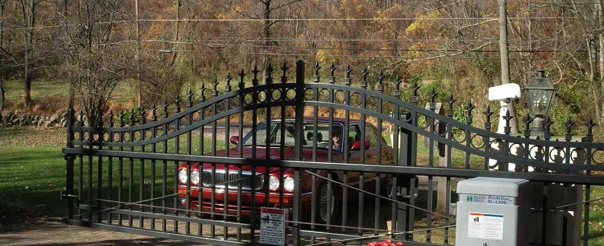 Monumental Iron Works ornamental driveway gate with scrolled top and vehicle