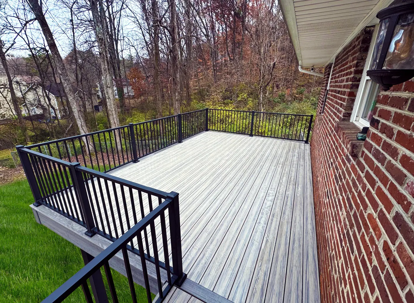 RailMaster aluminum railing on a composite deck beside a brick house