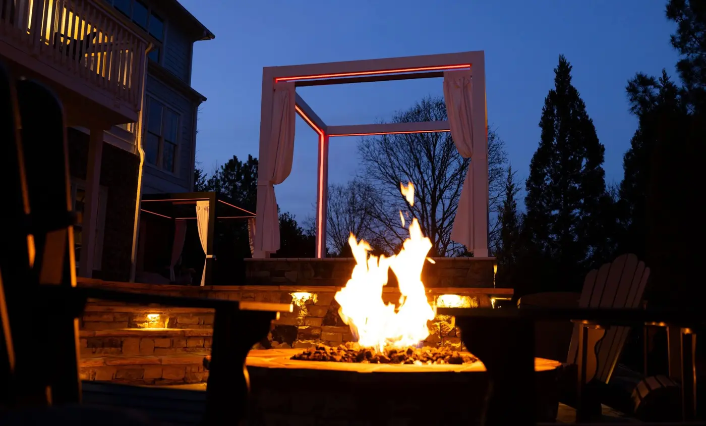 Outdoor fire pit framed by a modern structure at dusk