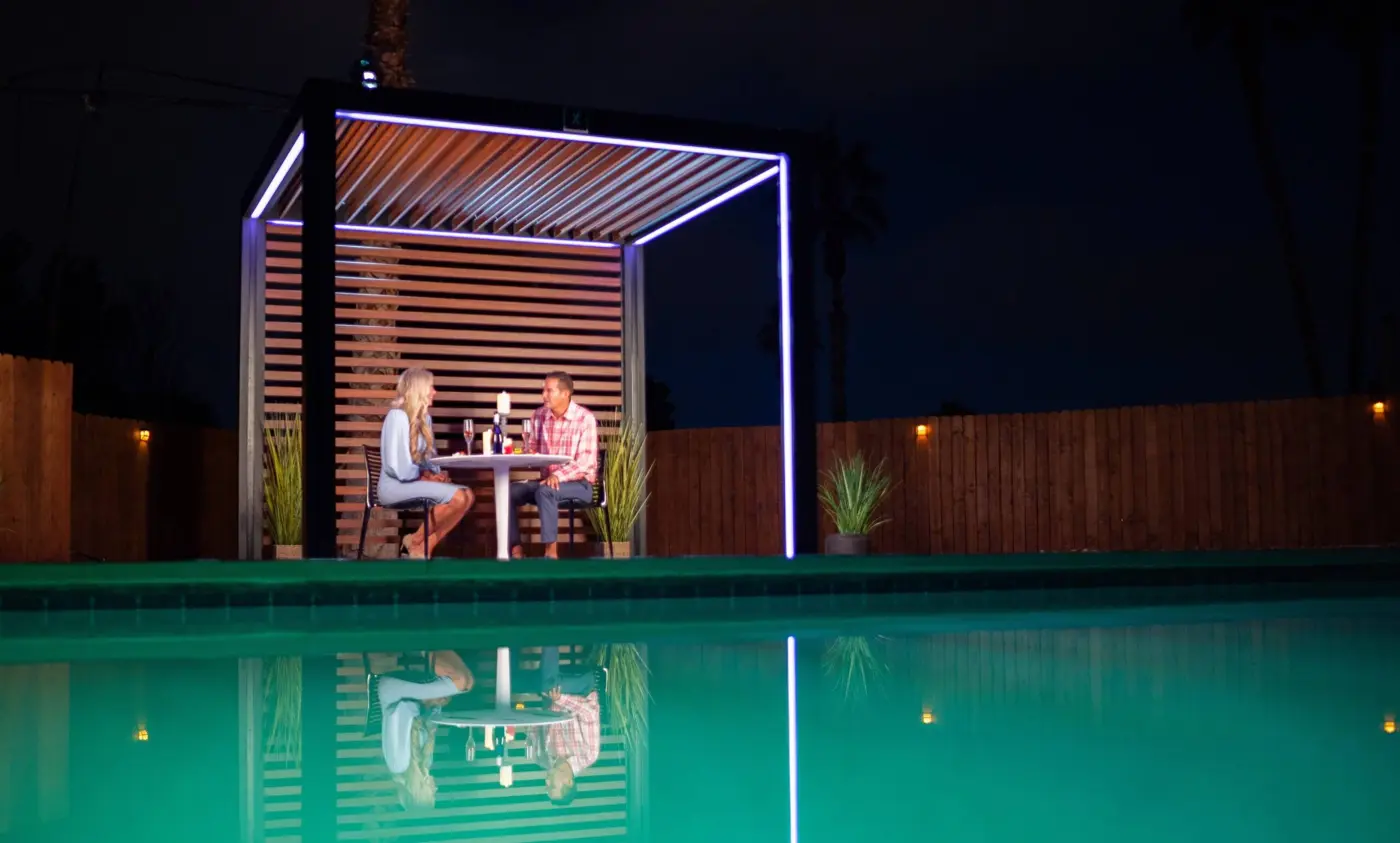 Illuminated pergola beside a glowing pool at night