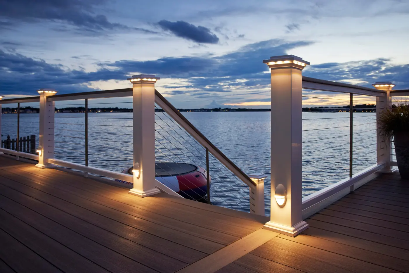 Lit railing post caps on a lakeside deck at dusk