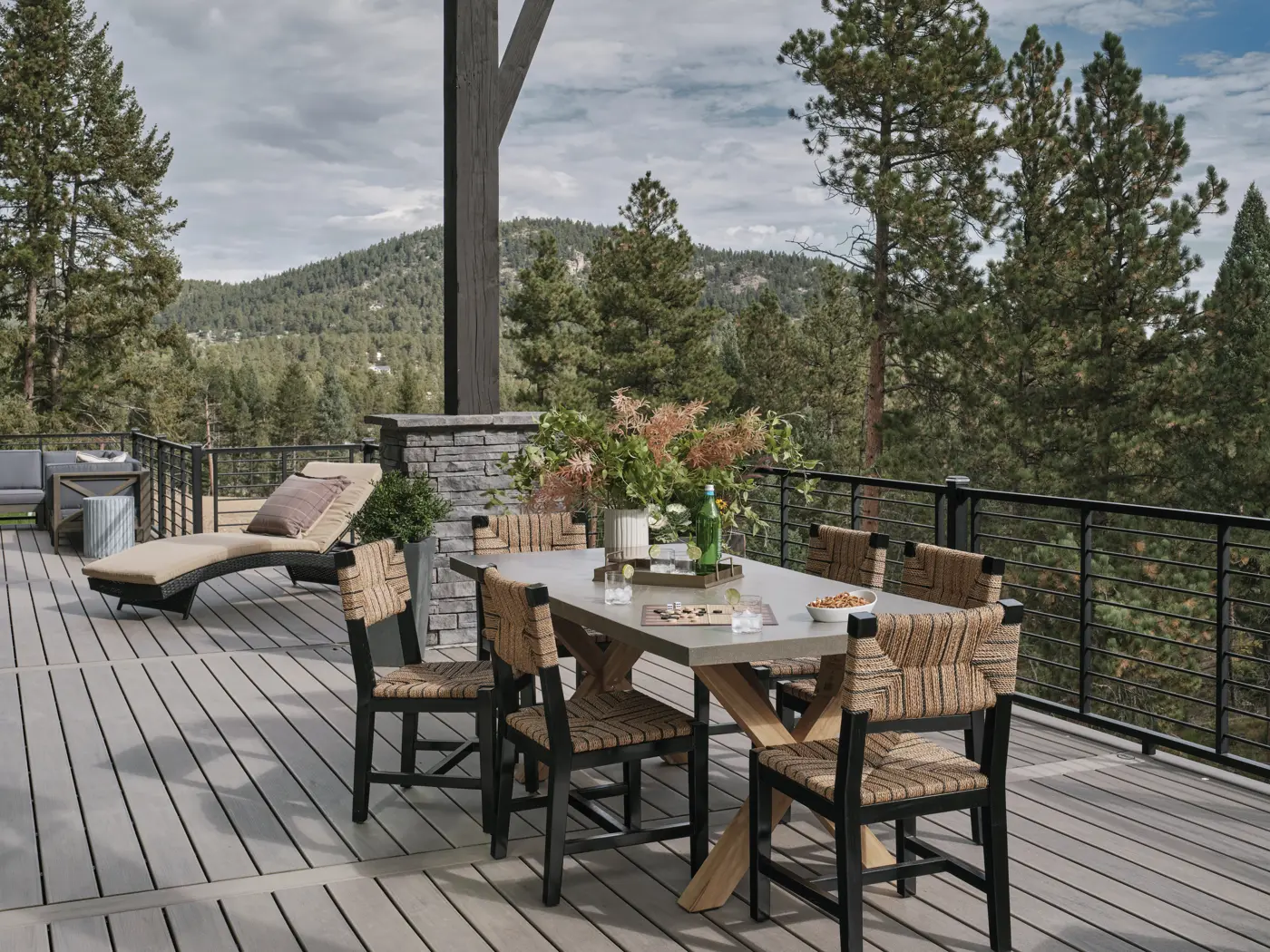 Dining deck with black railing overlooking forested hills