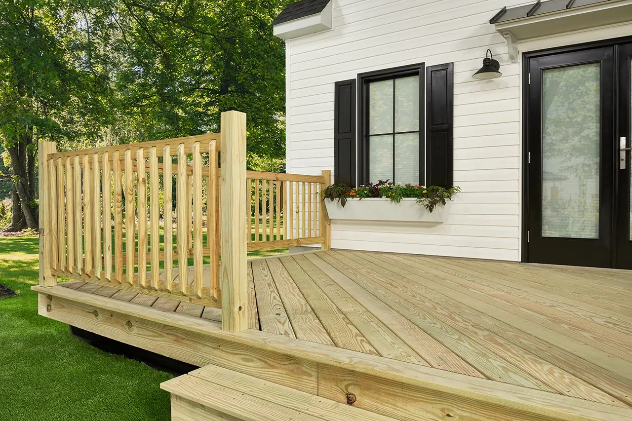 Pressure-treated pine deck with wood railing at a white house